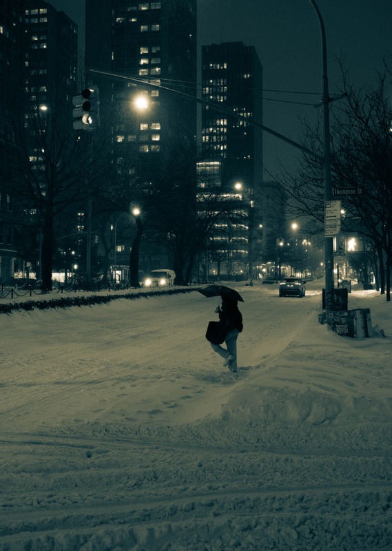 灯光下在积雪里行走的人
