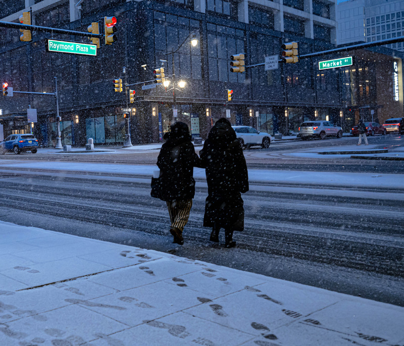 雪中路口并肩的两个人